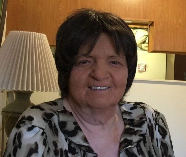 Photo of Cindy Umphries, smiling. She appears to be sitting at home in a dinette or living room.