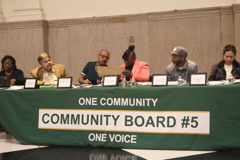 Members of Brooklyn Community Board 5 seated behind a meeting table in East New York. Members of Brooklyn Community Board 5 seated behind a meeting table in East New York.