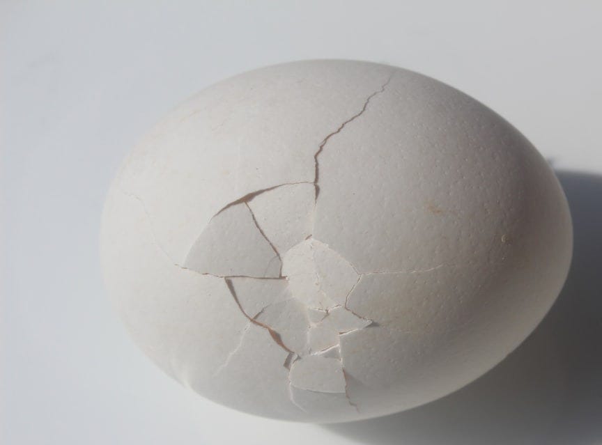 a cracked egg sitting on top of a white table