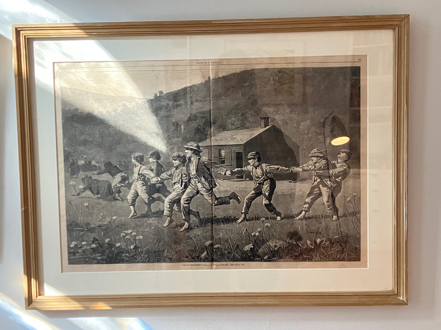 photograph of a framed print of Winslow Homer's Snap the Whip, where a line of boys hold hands to play a rural game photograph of a framed print of Winslow Homer's Snap the Whip, where a line of boys hold hands to play a rural game