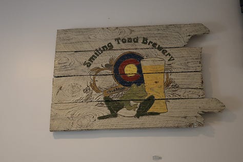 People drinking beer sitting down and standing up with frogs and toads in the background