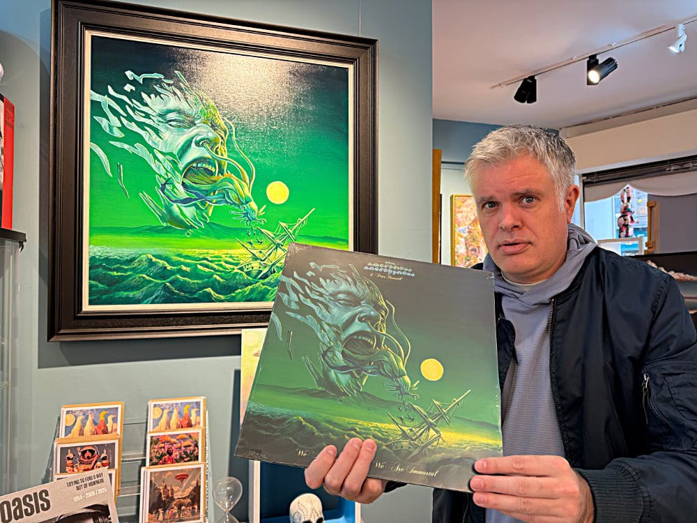 An artist holds a record infant of the painting that inspired the cover. It's a weird picture of a fragmented head spewing a space squid above a shipwreck in a turbulent sea.