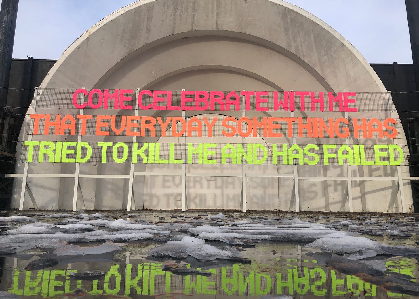 Image of a text installation using an excerpt from Lucille Clifton’s 1993 poem “won’t you celebrate with me” in neon letters at the Prospect Park Bandshell in Brooklyn, NY. It reads “Come celebrate with me that every day something has tried to kill me and has failed.” Image of a text installation using an excerpt from Lucille Clifton’s 1993 poem “won’t you celebrate with me” in neon letters at the Prospect Park Bandshell in Brooklyn, NY. It reads “Come celebrate with me that every day something has tried to kill me and has failed.”