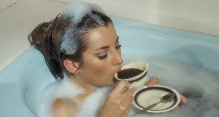 This may contain: a woman drinking from a cup in a bathtub