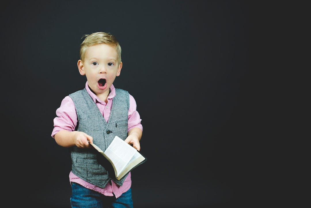 boy wearing gray vest and pink dress shirt holding book boy wearing gray vest and pink dress shirt holding book