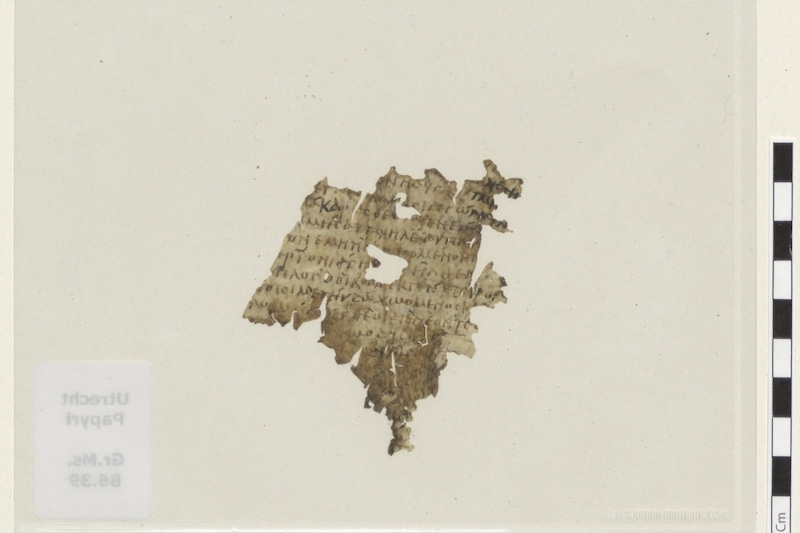 The reverse of the parchment fragment, about 6.6 by 7.7 centimetres, mounted between glass with a scale bar at right. The catalogue label reads Utrecht Papyri Gr. Ms. 66.39. The reverse of the parchment fragment, about 6.6 by 7.7 centimetres, mounted between glass with a scale bar at right. The catalogue label reads Utrecht Papyri Gr. Ms. 66.39.