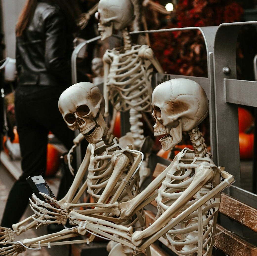 a couple of skeletons sitting on top of a wooden bench