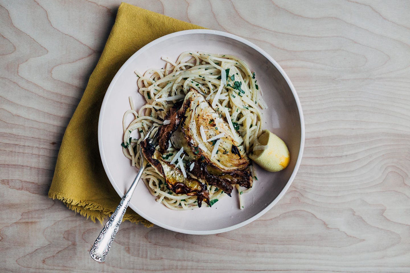 A bowl of pasta with a cabbage wedge