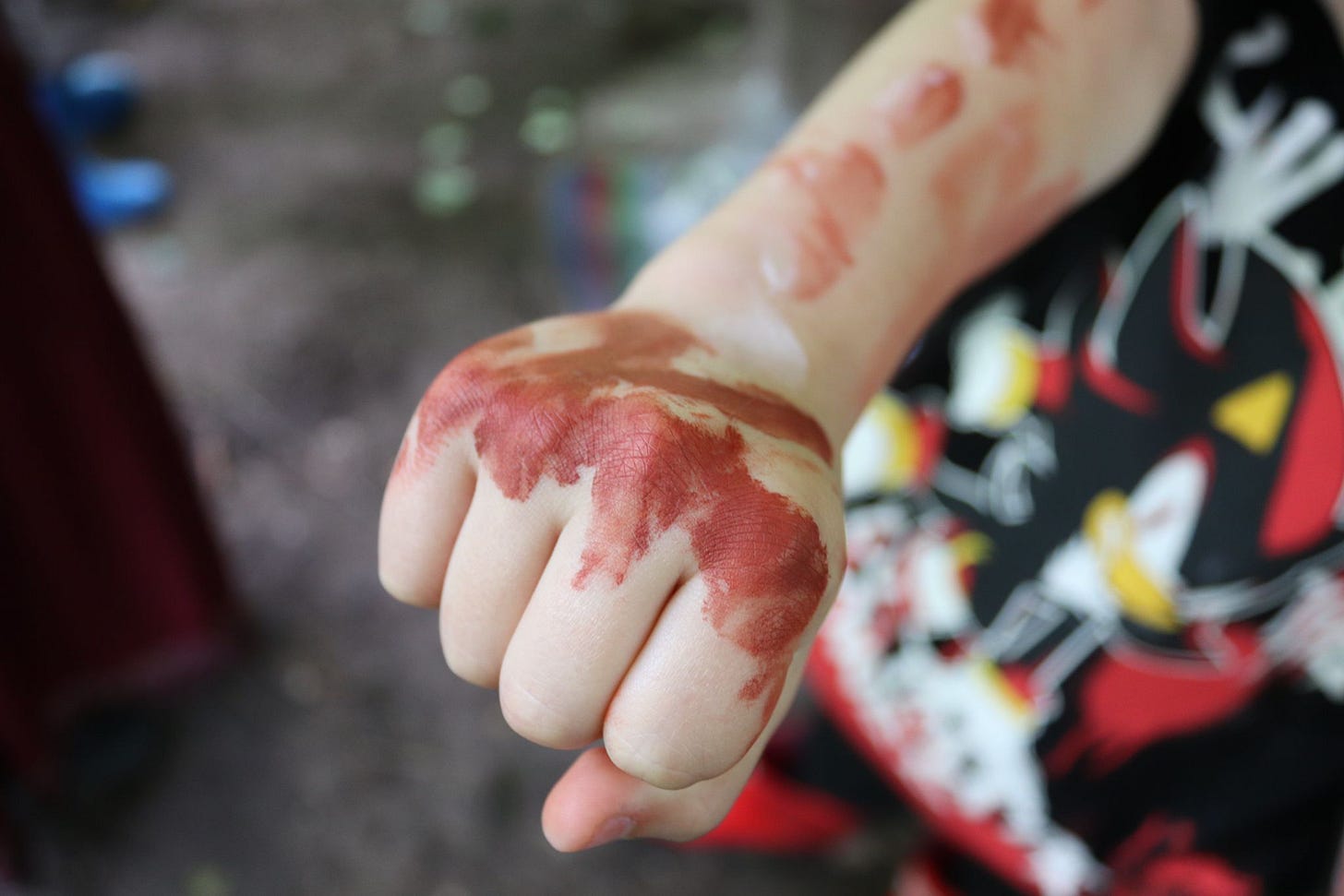 Child's arm going into the camera with face paint on