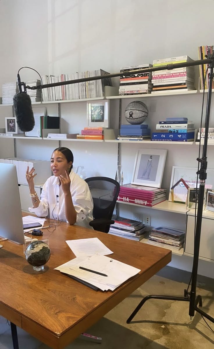 This may contain: a woman sitting at a desk in front of a computer