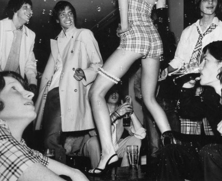 This may contain: a group of women standing around each other in front of a man on the dance floor
