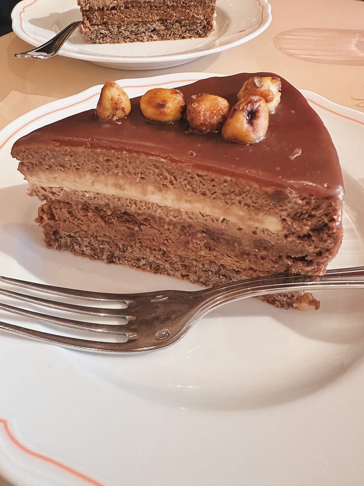 Slice of layered chocolate Gianduia cake and paninetti with prosciutto and cheese beside a matcha latte at Sant Ambroeus, Aspen.