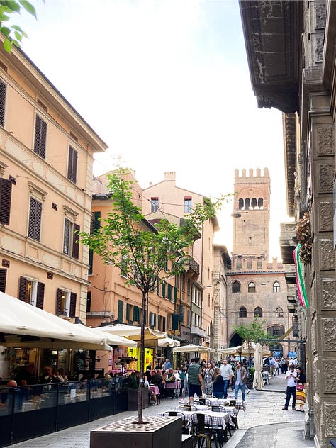 Photographs of views from the street in Bologna showing historic towers and a verdant florist.