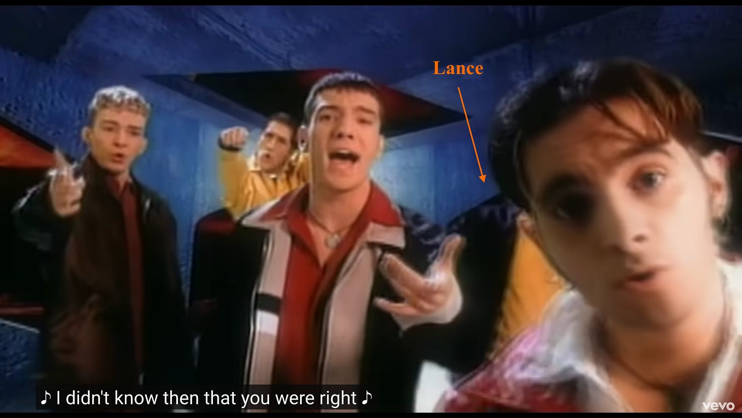 As the camera has slightly moved, Lance can be seen just barely, behind Chris. An orange arrow with "Lance" above it points out his torso.