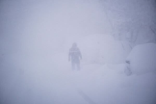 A person is barely visible through a barrage of snow. A person is barely visible through a barrage of snow.