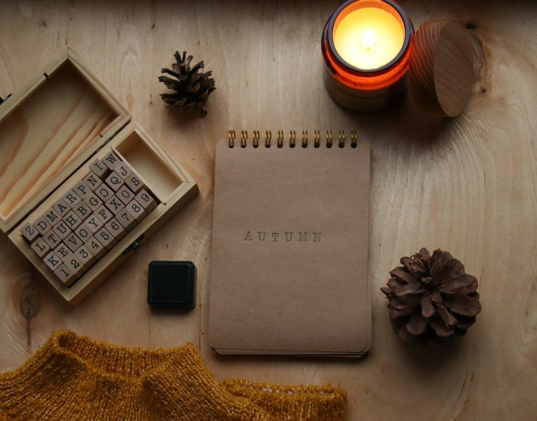a table with a notebook, candle, and sweater on it