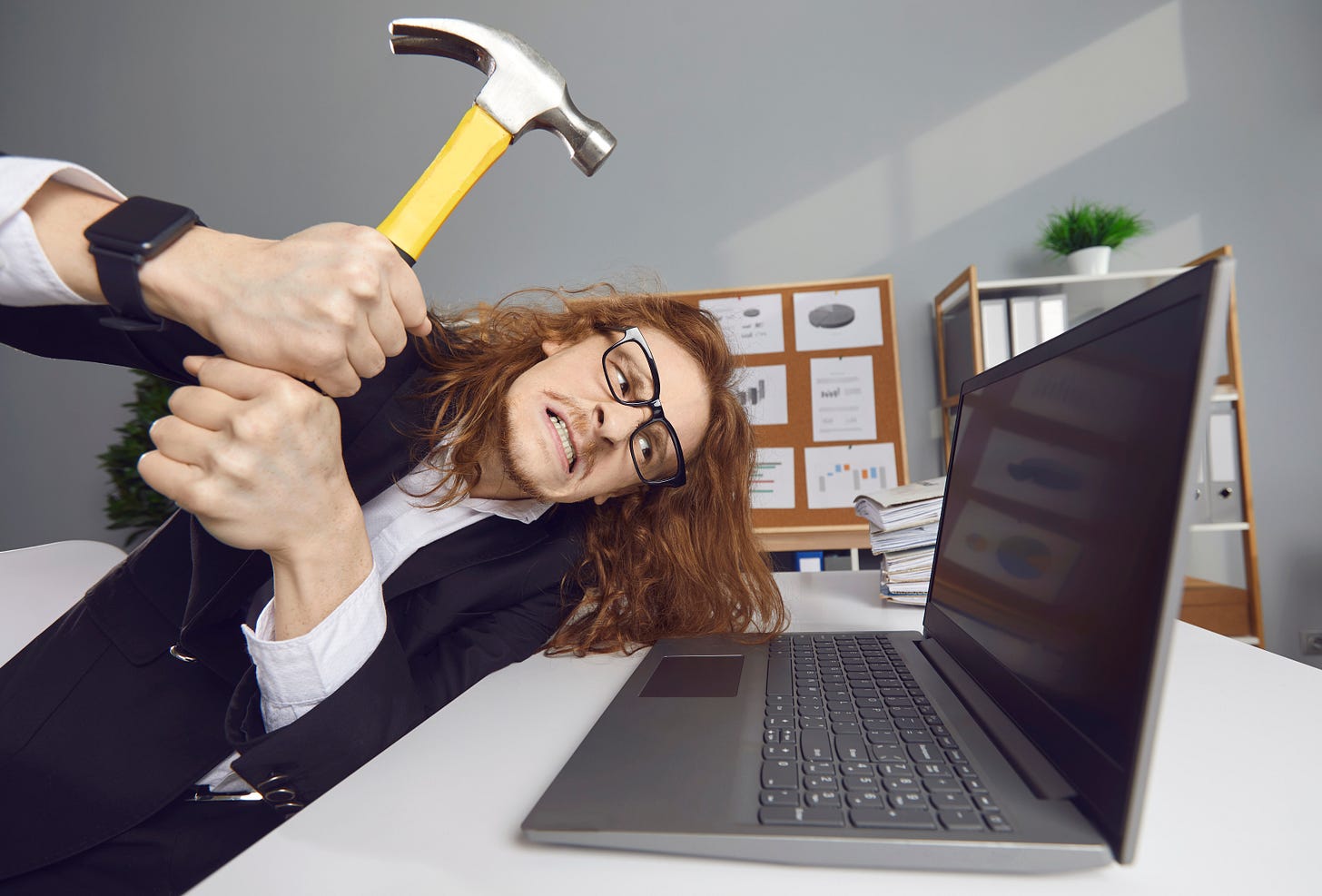 A man raising a hammer over a laptop. A man raising a hammer over a laptop.