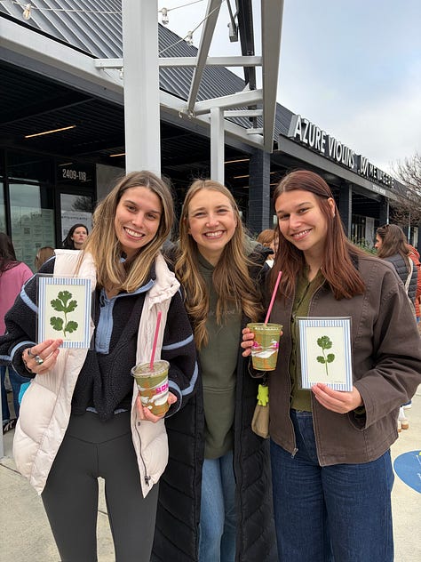 Lots of people holding a green smoothie at an in-person event for Grace & Greens
