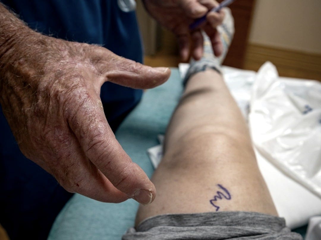 A medical professional examines a knee injury A medical professional examines a knee injury