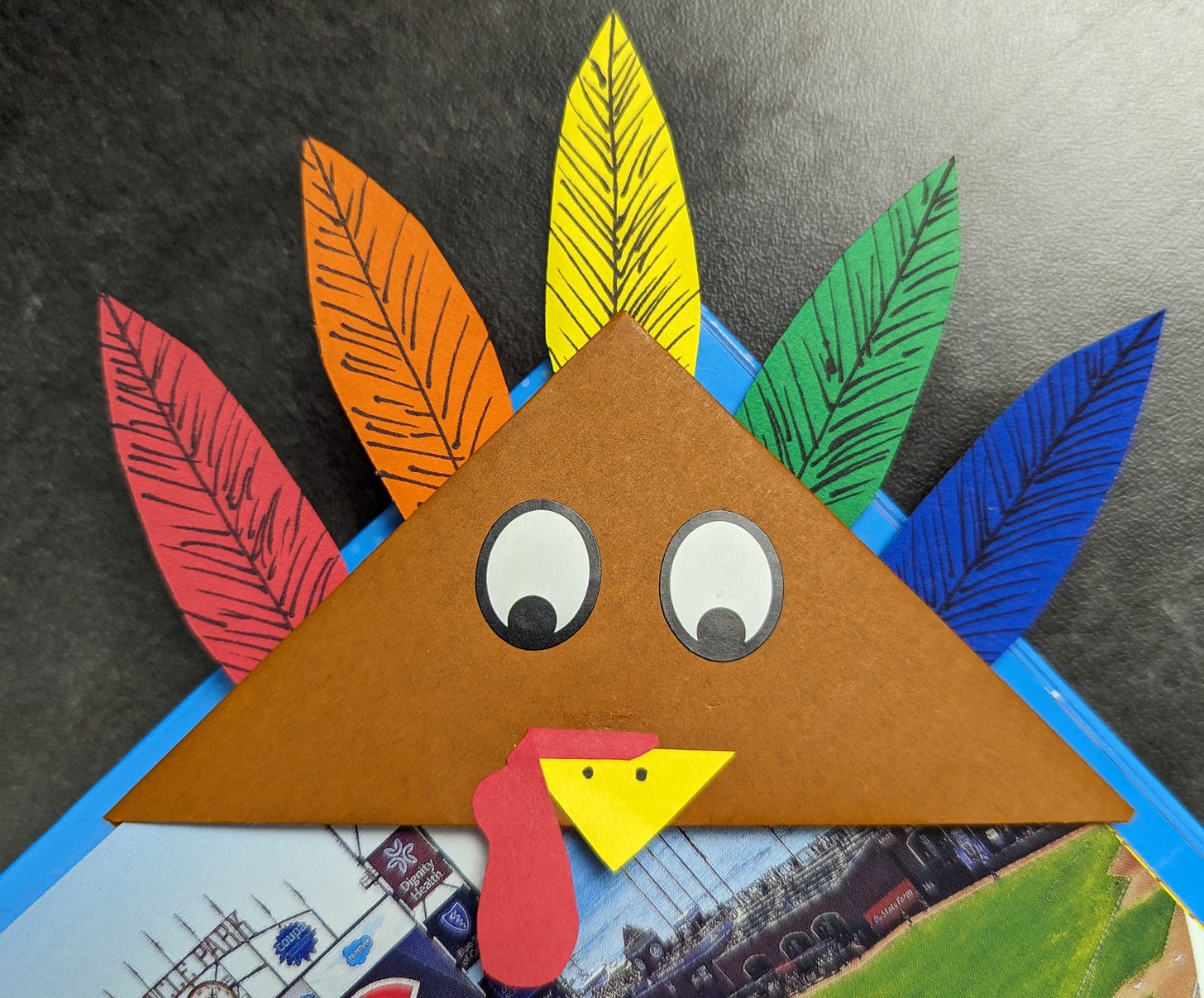 A triangular bookmark on the corner of a book page. The bookmark is decorated to look like a turkey.