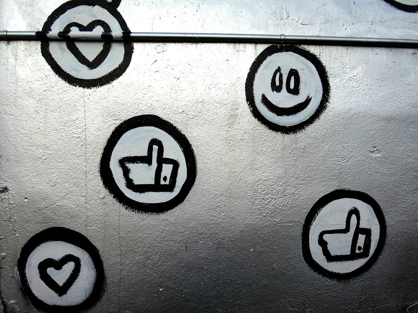 Black and white social media emojis painted on a silver background or wall