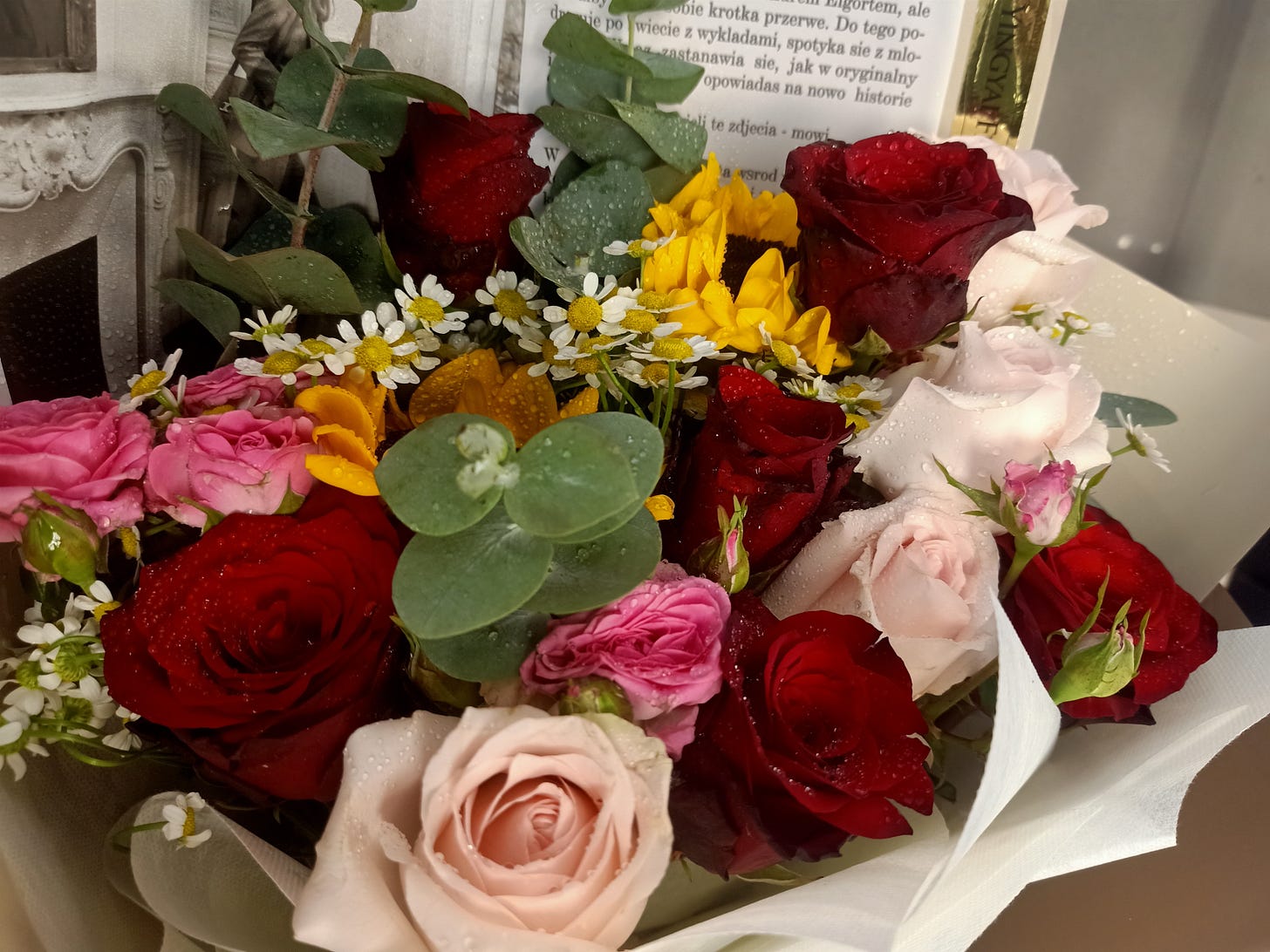 a bouquet of roses, sunflowers, eucalyptus and more with water droplets