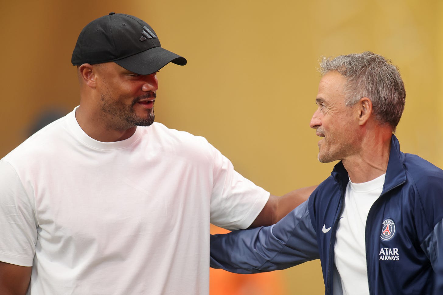 Vincent Kompany puts his arm around Luis Enrique's back and smiles.