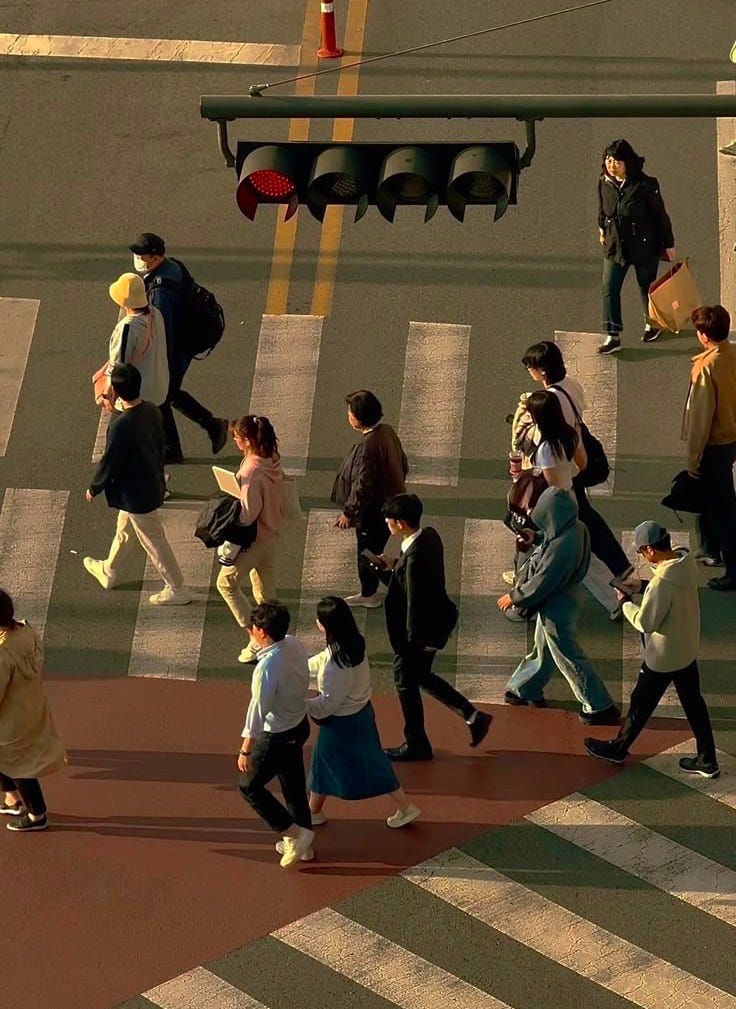 This may contain: many people are crossing the street at an intersection