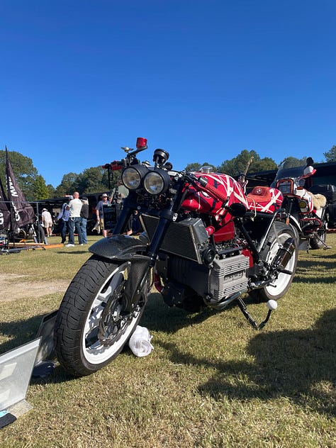 an artist doing a large live sketch of a concept bike; the race track; vintage bikes, and a cigar