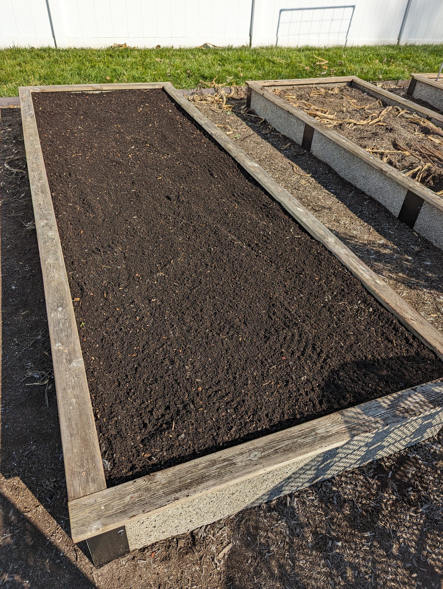 The garden bed on the left has had three or four cart loads of finished compost spread ont othe bed and raked flat.  The bed on the right hasn't had compost applied yet.  