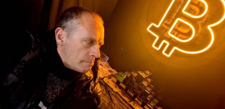 Photo of the author looking at a pile of fake gold and a Bitcoin logo.