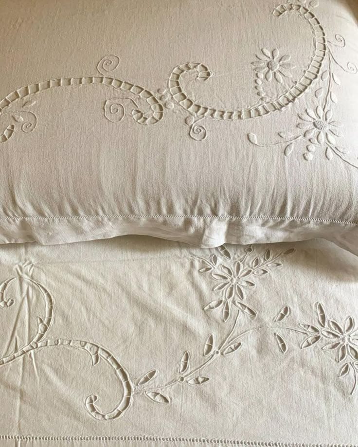 This may contain: two white pillows sitting next to each other on top of a bed