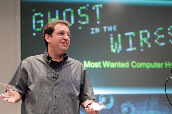 A man wearing glasses with a microphone clipped to a gray short-sleeve shirt. A man wearing glasses with a microphone clipped to a gray short-sleeve shirt.
