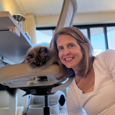 A woman with brown hair and her tabby and white cats