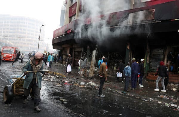 People walk on a street that is covered in debris.
