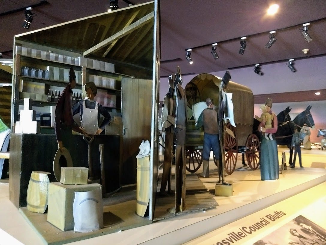 Scene of metal sculptures showing 19th century grocery intierior and people loading wagon Scene of metal sculptures showing 19th century grocery intierior and people loading wagon