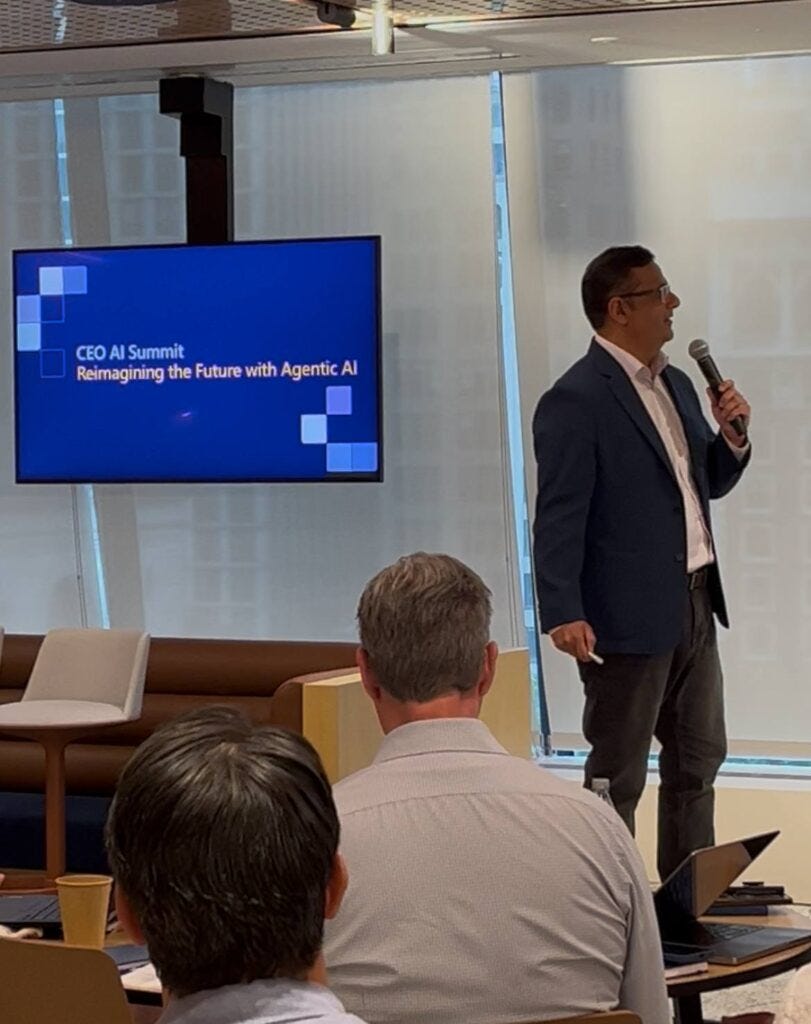 A man in a blue blazer is speaking into a microphone in front of an audience at the \ A man in a blue blazer is speaking into a microphone in front of an audience at the \