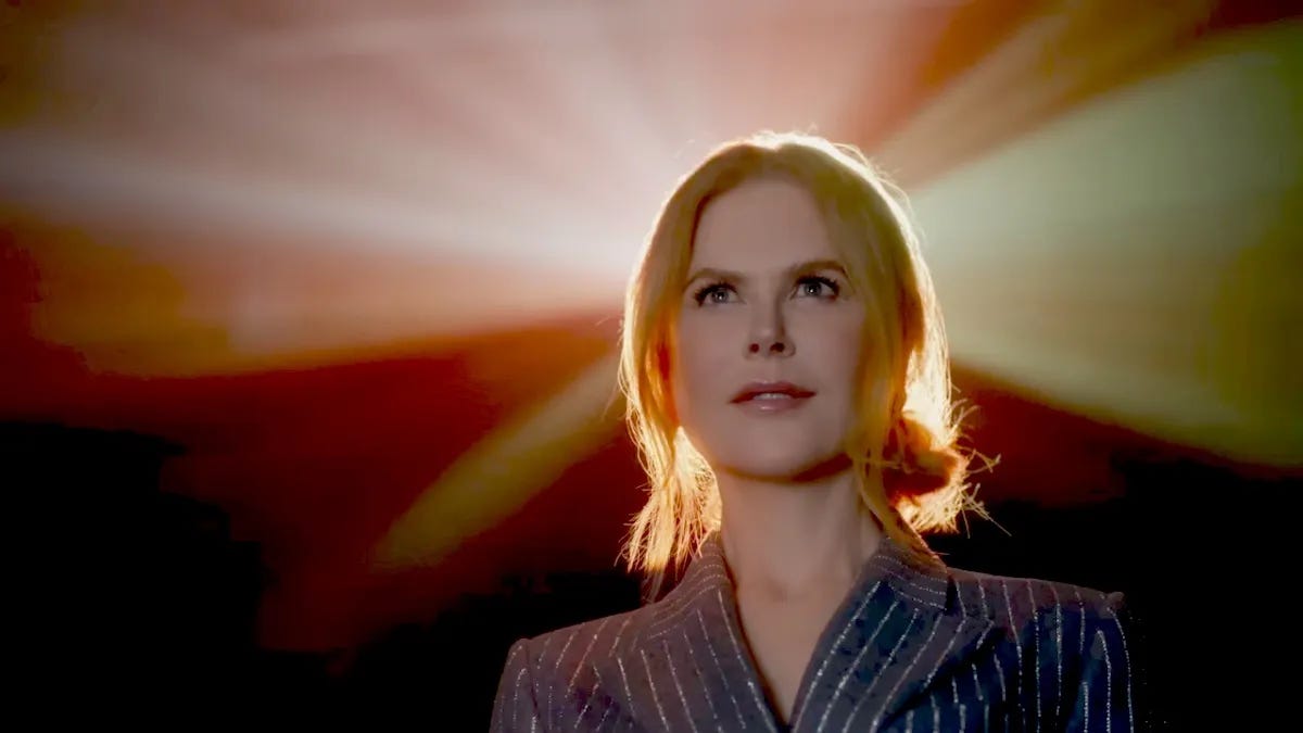 Nicole Kidman in an AMC, backlit and wearing a sparkly silver suit.