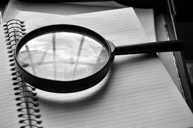 Magnifying glass on an open ring bound journal Magnifying glass on an open ring bound journal