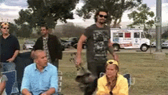 a group of people are gathered in a park with a food truck in the background .