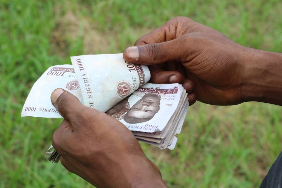 Hands of a person holding and counting a wad of 1,000 naira notes Hands of a person holding and counting a wad of 1,000 naira notes