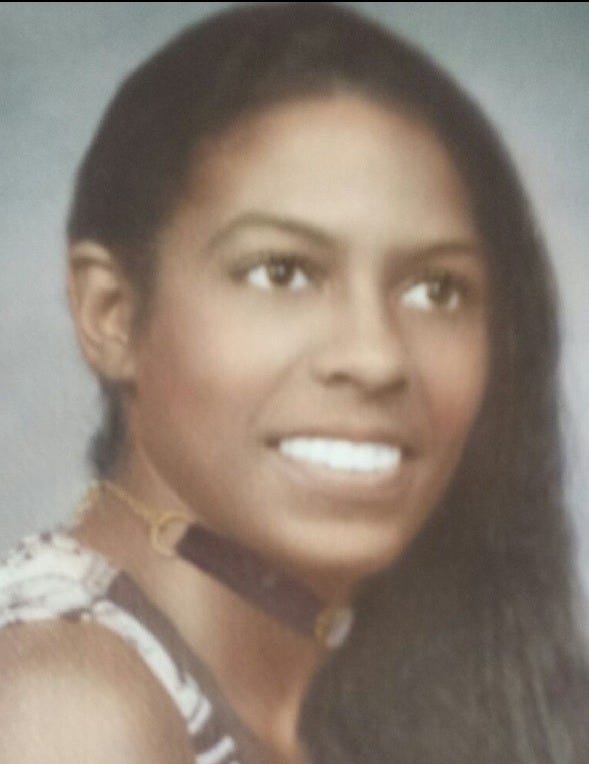 Hazy portrait of a woman with long black hair. She is wearing a short choker necklace and looking slightly right of the camera lens