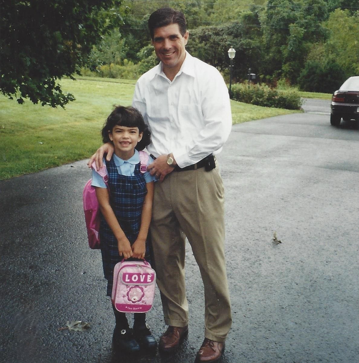 Dad posed in the driveway with his 6-year-old daughter on her first day of school. A Dodge Intrepid is barely visible in the background.