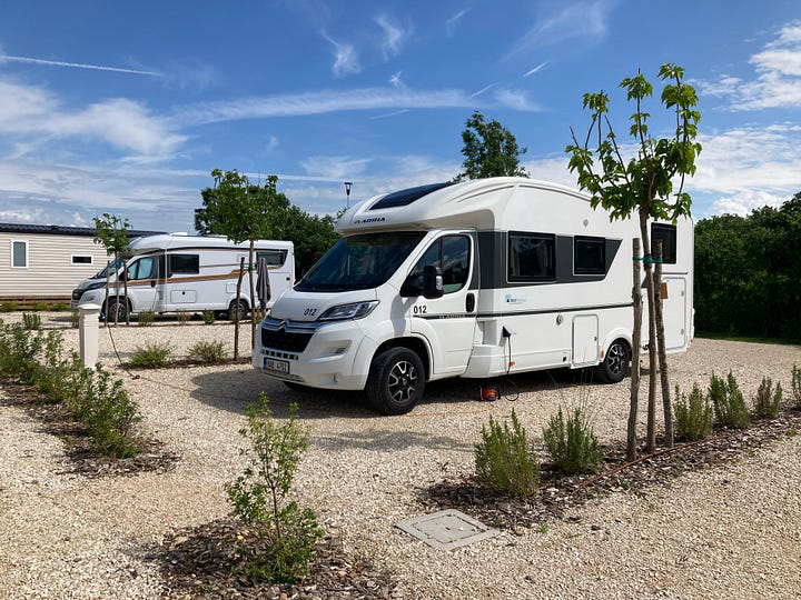 Photo of campers lined up in a mostly bare lot, and scenic image of rooftops of Verona's old quarter.
