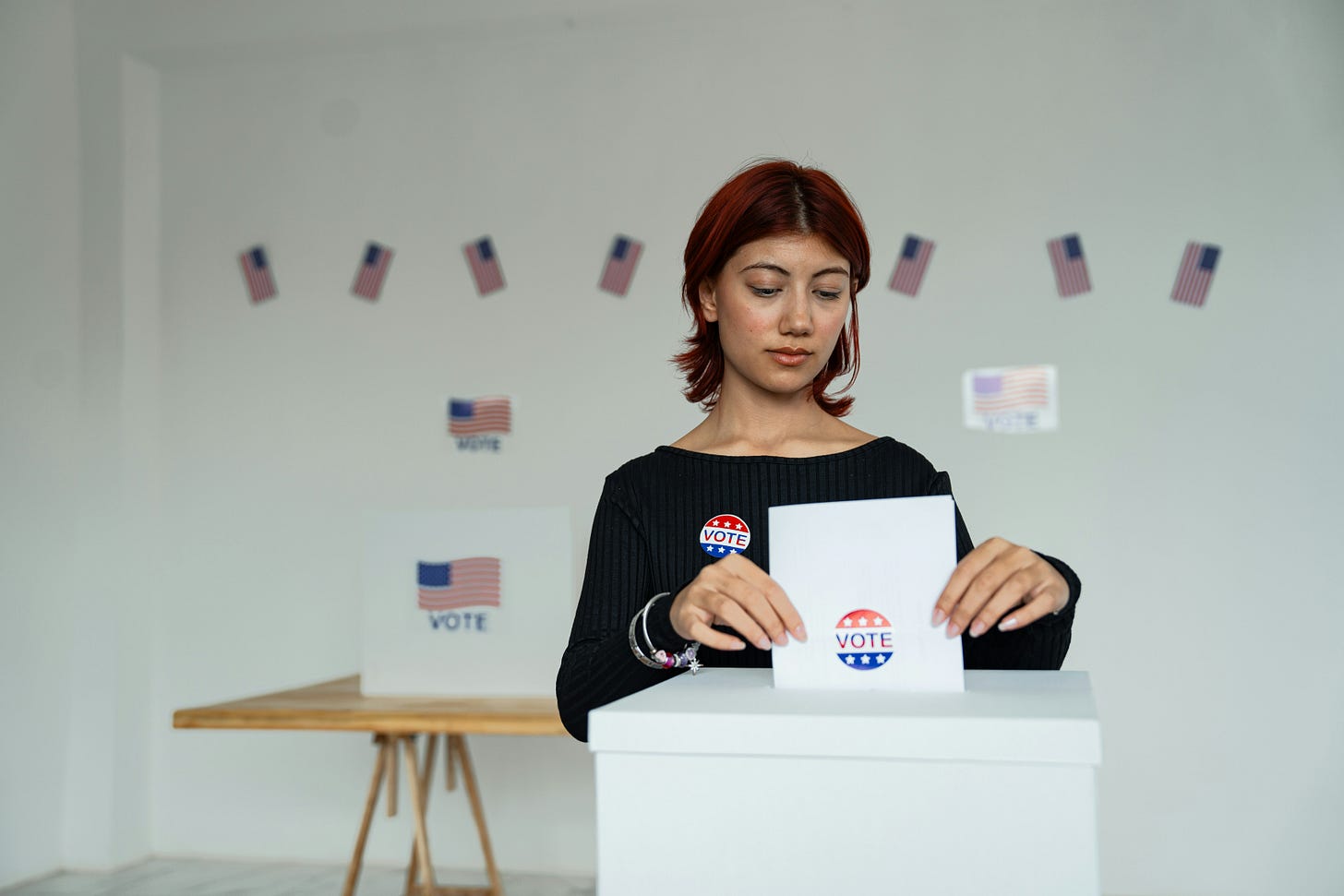 Woman of color casing her vote in a white room at a polling station