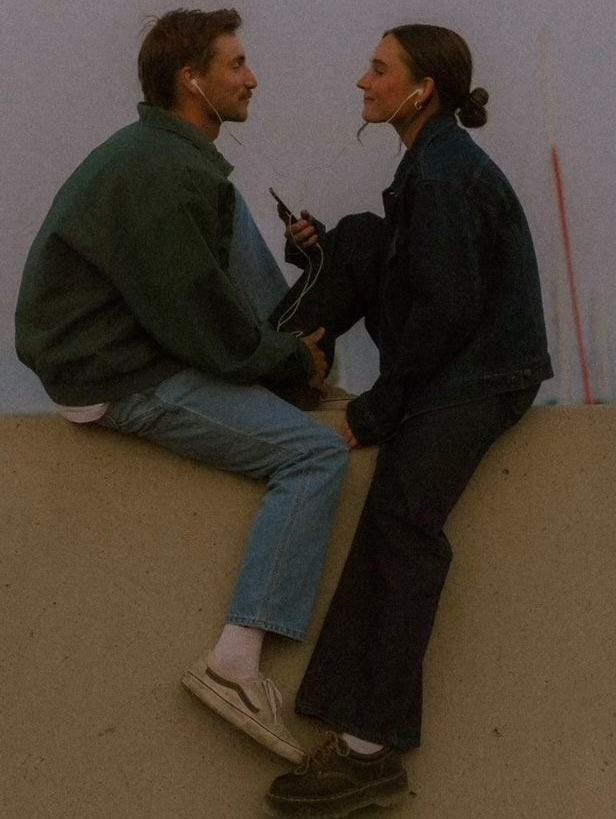 This may contain: two people sitting on top of a wall talking