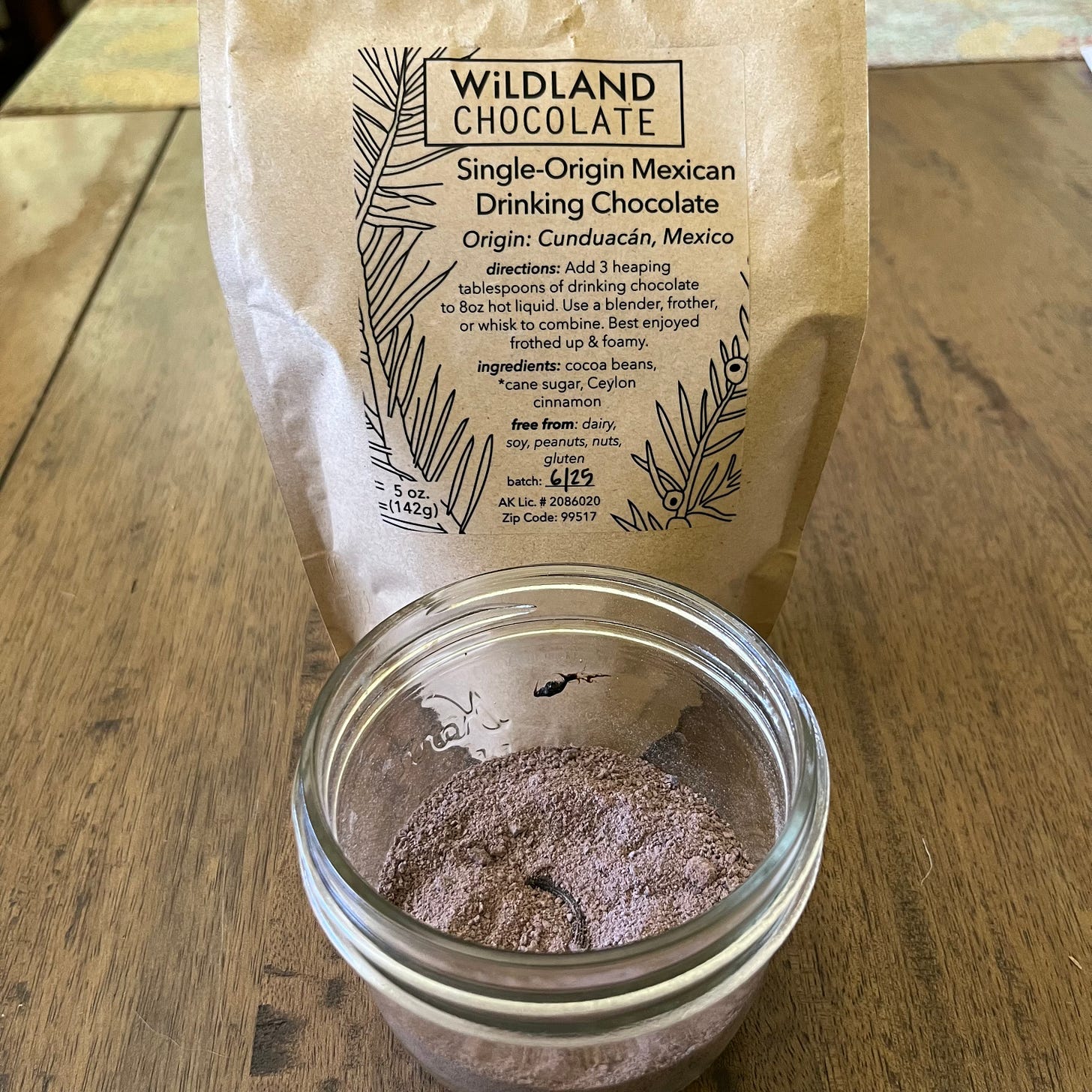 Unlidded jars showing drinking chocolate powder, vanilla and a cap of labdanum. Wildland chocolatepackaging in the background.