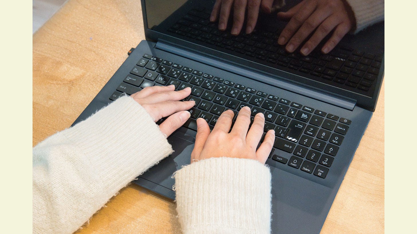 A woman wearing a sweater using a laptop A woman wearing a sweater using a laptop