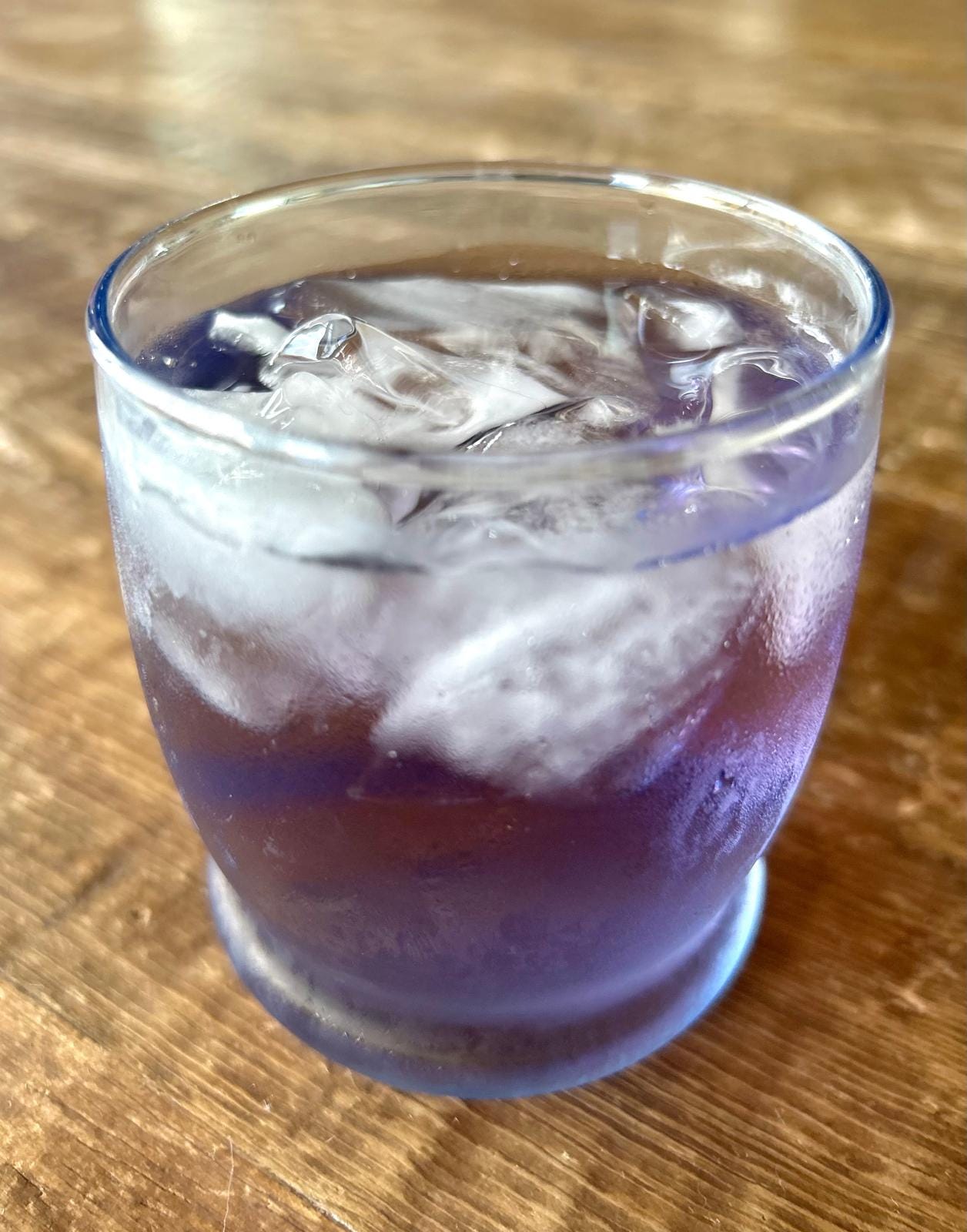 a glass of purple iced basil tea on a table a glass of purple iced basil tea on a table