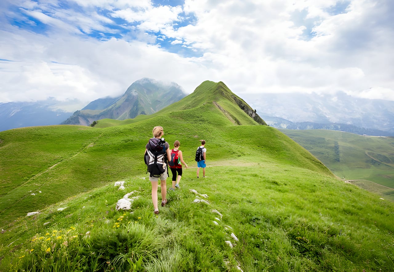 3 friends hiking across a grassy expanse on a sunny day. 3 friends hiking across a grassy expanse on a sunny day.